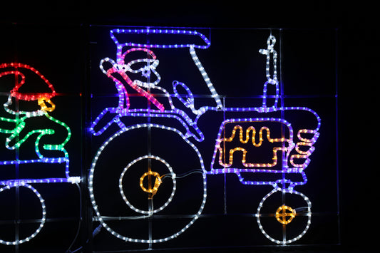 Julenissen i blå traktor alv og juletre på henger